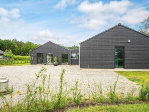 A modern building with a gravel driveway, large windows, and a well-maintained lawn. - 5 Star Holiday Home in Farvang (Farvang)