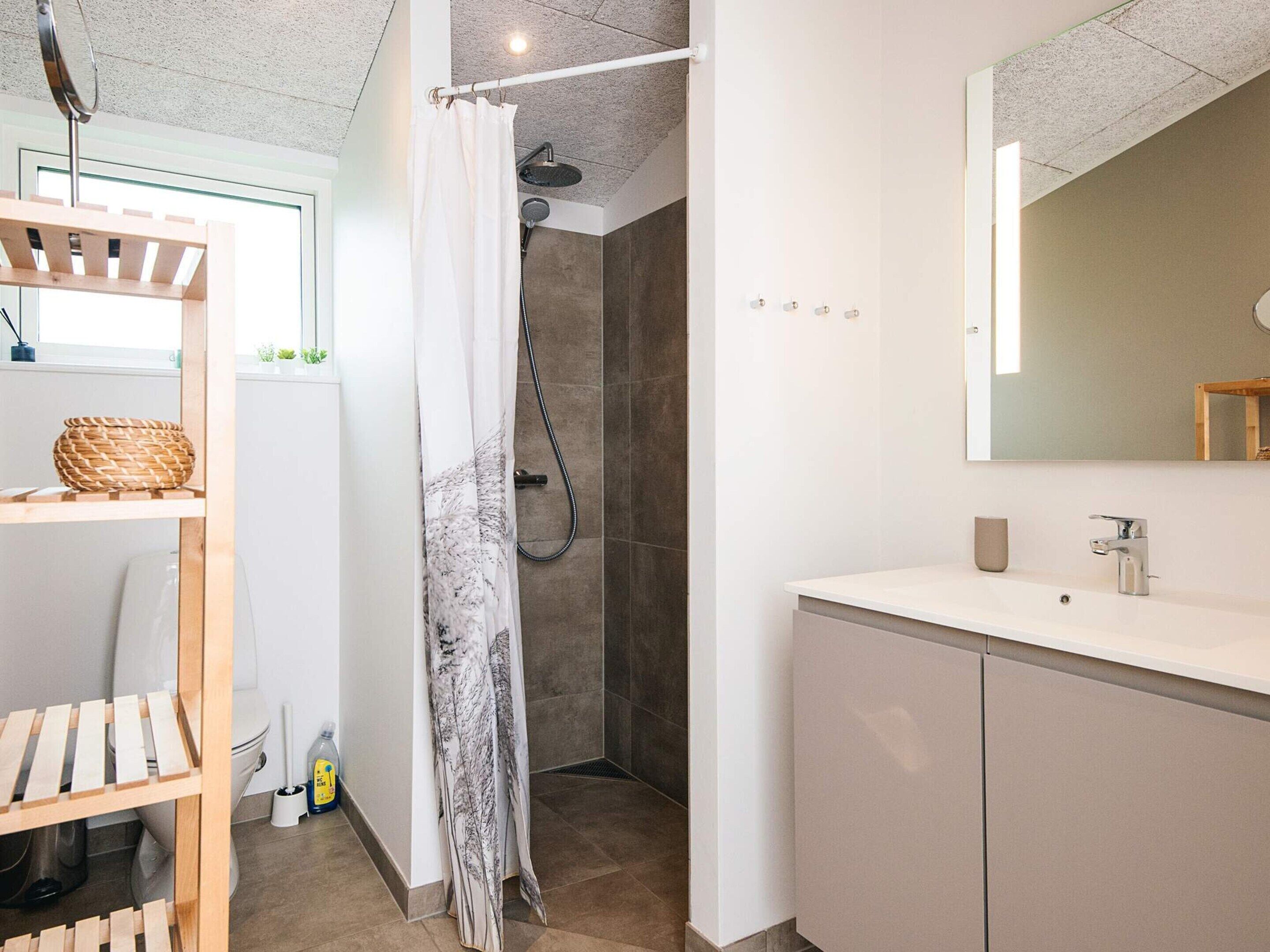 Een moderne badkamer met douche, toilet en wastafel.