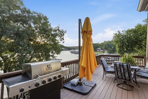 Une terrasse équipée d’un barbecue, de mobilier d’extérieur et offrant une vue sur un lac.