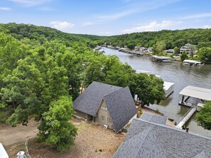 Une propriété située au bord de la rivière, avec des bateaux amarrés, une maison dotée d’un toit en pente et une v égétation luxuriante.