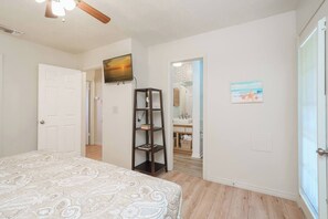 Ein Schlafzimmer mit Bett, Bücherregal, Fernseher und einem durchgegangenen Tür sichtbaren Badezimmer.