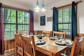 A dining area with a wooden table set for six, surrounded by wooden chairs, with two pendant lights above. - Beary Peaceful Smokies:Hot-Tub, Games & Pools (Pigeon Forge)