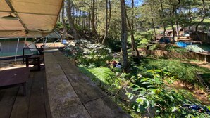A campsite with a tent, a picnic table, and a wooden deck. - Cozzy Saprag Riverside Pangalengan (Pangalengan)