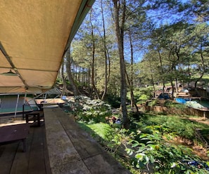 Een camping met een tent, een picknicktafel en een houten terras.