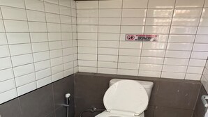A small, tiled bathroom with a white toilet, a hand sanitizer dispenser, and a sign prohibiting smoking. - Cozzy Saprag Riverside Pangalengan (Pangalengan)