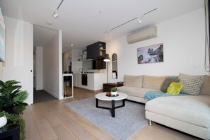 Ein modernes Wohnzimmer mit einer Couch, einem Couchtisch und Blick in die Küche.