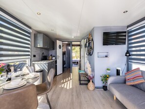 A modern interior with a dining area, kitchen, and living space, featuring a sofa, TV, and a view through the window. - Houseboat in the marina of Volendam. (Volendam)