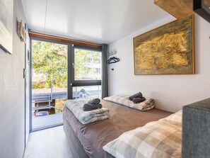A room with two beds, a painting, and a view of the outdoors. - Houseboat in the marina of Volendam. (Volendam)