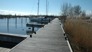 Un muelle de madera que se adentra en aguas tranquilas, con barcas amarradas al final.