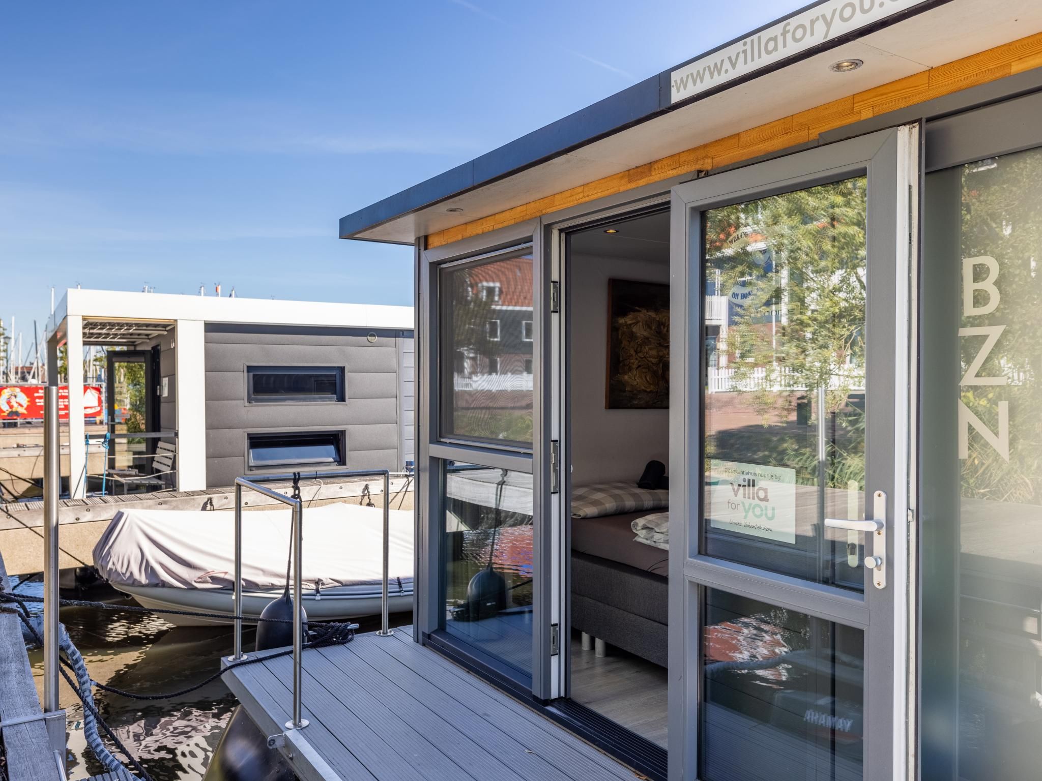 Een moderne villa met een glazen deur, een houten terras en een ruim buitengebied.