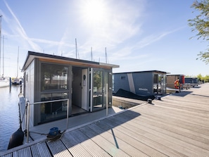 Un port de plaisance moderne, doté d’un bâtiment aux murs de verre et d’une terrasse en bois.
