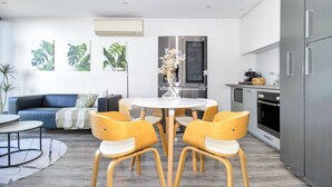A modern living space with a dining area, a sofa, and a kitchen. - Top-Floor Apartment with Balcony - High Street (Prahran)