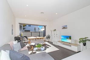 Ein modernes Wohnzimmer mit einer Couch, einem Esstisch und einem Fernseher.
