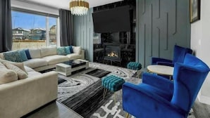 Ein modernes Wohnzimmer mit Sofa, Couchtisch, blauem Sessel und Kamin.