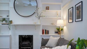 Ett vardagsrum med en öppen spis, en soffa, ett soffbord och en lampa.