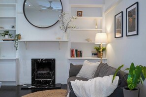 Ein Wohnzimmer mit Kamin, einer Couch, einem Couchtisch und einer Lampe.