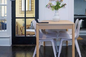 Ein Essbereich mit einem Holztisch, weißen Stühlen und einer Vase mit Blumen.