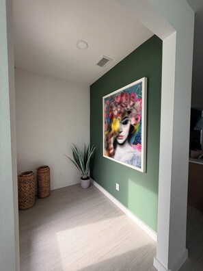 Ein Zimmer mit grüner Wand, einem gerahmten Kunstwerk, einer Topfpflanze und zwei gewebten Körben.