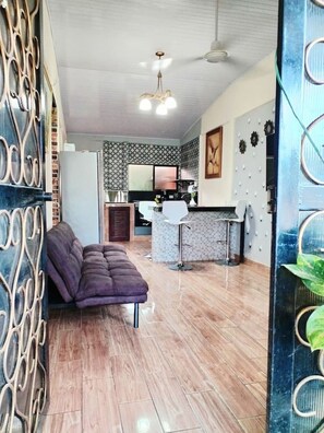 A spacious living area with a sofa, a kitchen in the background, and a decorative wall. - 2BR Home Near Ocotal Beach | 5 Min to the Beach, 8 Min to Coco (Coco)