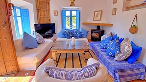 A cozy living room with a sofa, a coffee table, a television, and a fireplace. - La Casita in Frigiliana (Frigiliana)