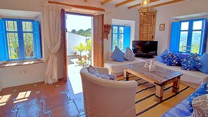 A room with a wooden ceiling, a sofa, a TV, and a window with blue shutters. - La Casita in Frigiliana (Frigiliana)