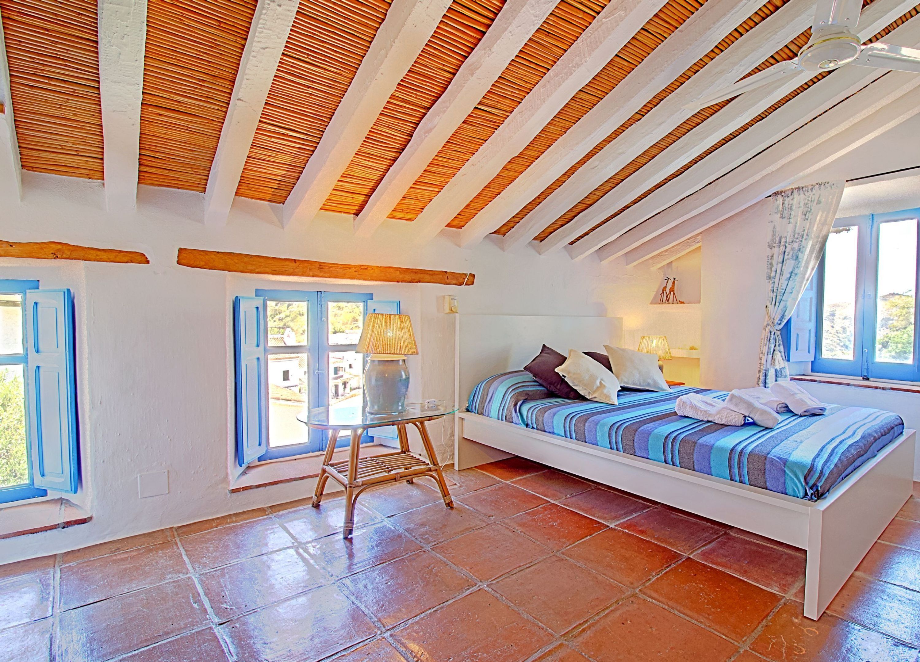 A bedroom with a bed, a table, and a chair.
