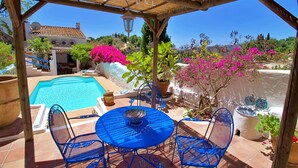 A covered outdoor area with a pool, blue metal chairs, and potted plants. - La Casita in Frigiliana (Frigiliana)