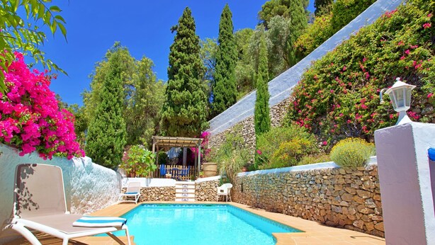 A swimming pool with a stone wall, a lounge chair, and a pergola with a view of the pool. - La Casita in Frigiliana (Frigiliana)