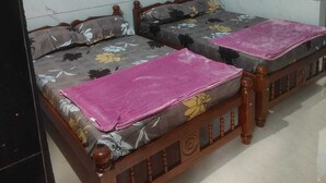 Una habitación con dos camas de madera, un ventilador de techo y un aire acondicionado.