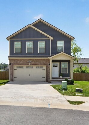 A two-story residential house with a garage, a front porch, and a well-maintained lawn.