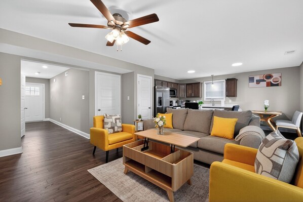 Un salon comprenant un canapé, des fauteuils, une table basse et un ventilateur de plafond.