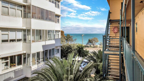 A multi-story building with balconies, a staircase, and a view of the sea. - Beachfront Marine Parade - Rooftop BBQ - Luna Park (Saint Kilda, Victoria, AU)