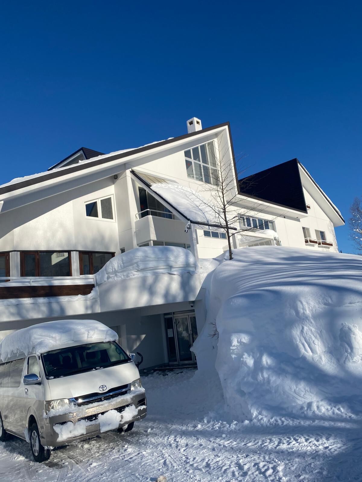 A modern two-story house with a garage, covered in snow.