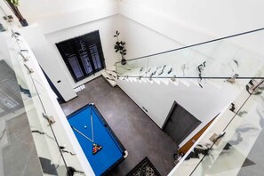 A pool table in a room with a window and a potted plant. - Acadia 5BR (Banglamung)