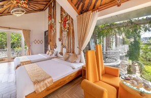 A bedroom with a bed, two chairs, a glass table, and a view of greenery. - MAC VALLEY DALAT HOTEL (Xuan Huong - Da Lat)