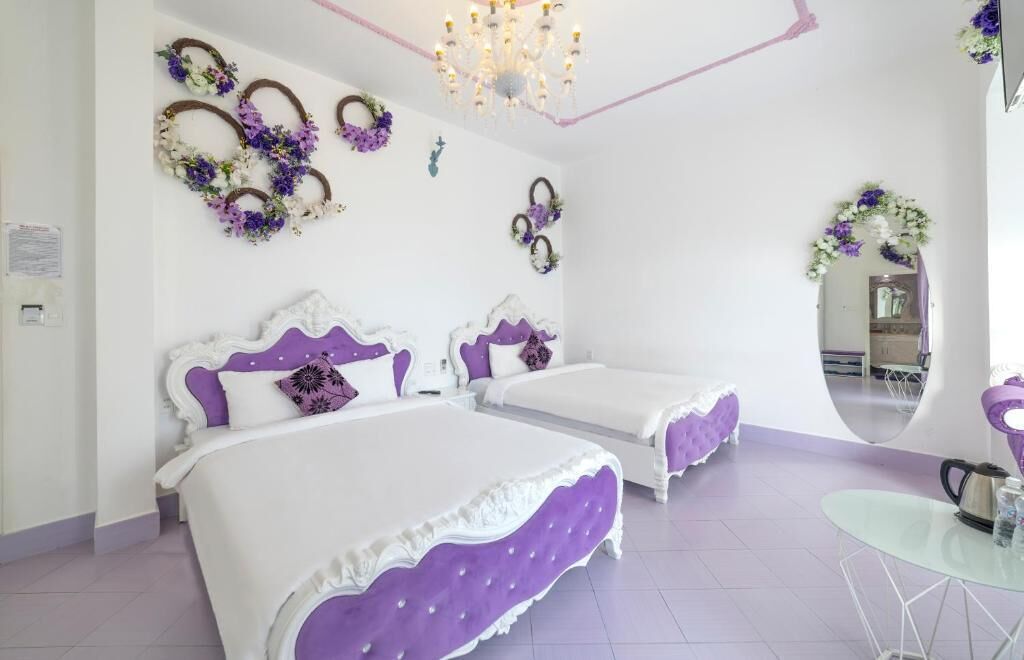 A bedroom with two beds, a chandelier, and decorative wall art.