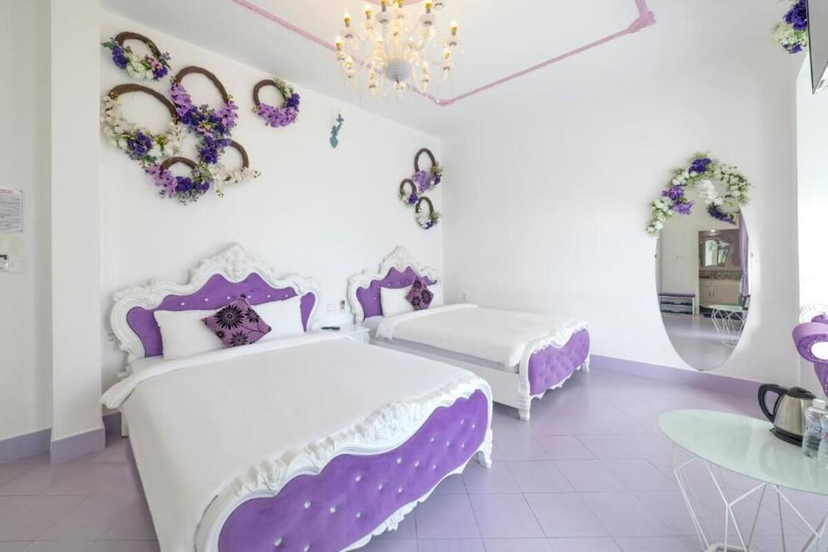 A bedroom with two beds, a chandelier, and decorative wall art.