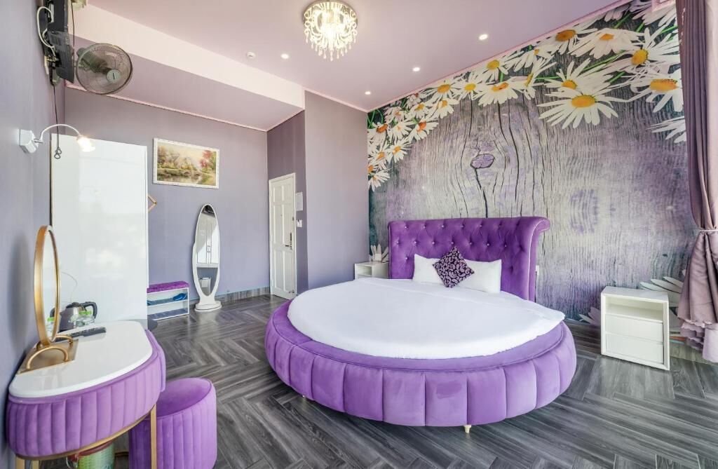 A bedroom with a round bed, a vanity with a mirror, and a wall mural.