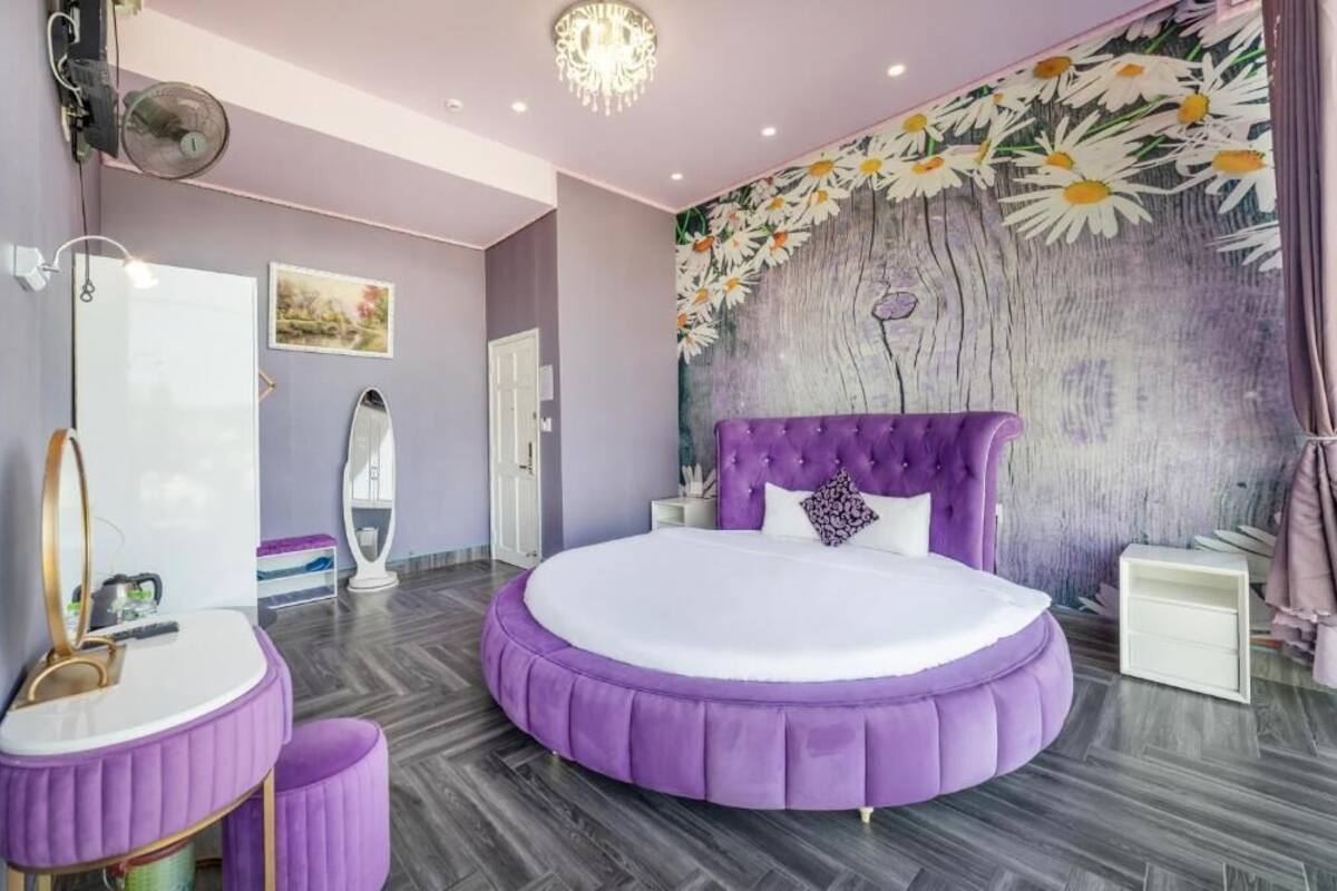 Quarto com cama redonda, toucador com espelho e um mural na parede.