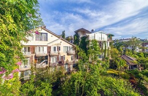 A multi-story building with balconies, surrounded by lush greenery and trees. - MAC VALLEY DALAT HOTEL (Xuan Huong - Da Lat)