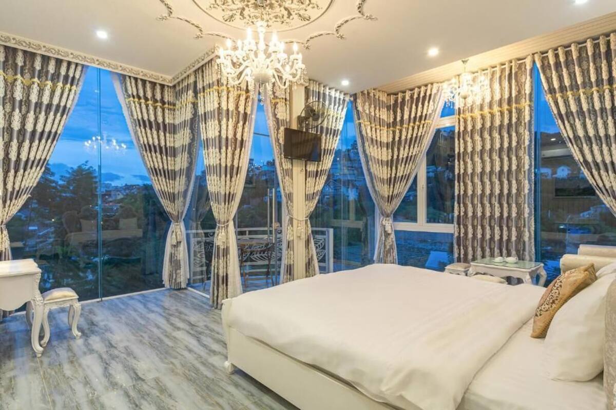 Un dormitorio con una cama grande, un candelabro y cortinas.