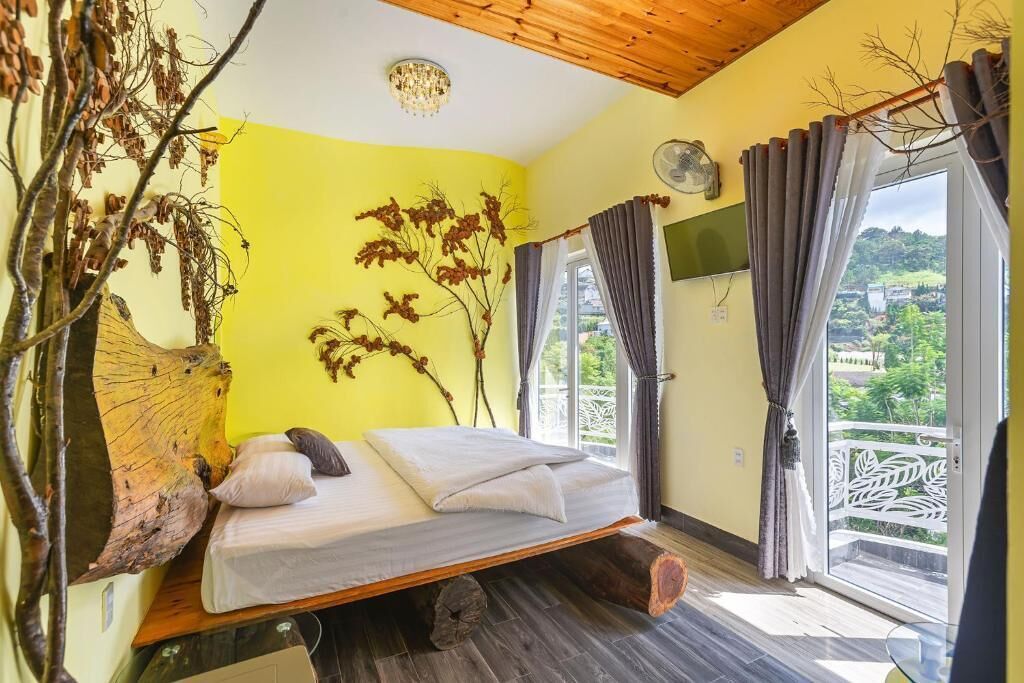 A bedroom with a bed, a wooden ceiling, a window with curtains, and a view of greenery outside.
