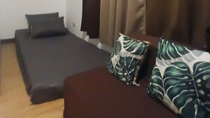 Een kamer met een bed, een klein tafeltje en een raam met gordijnen.