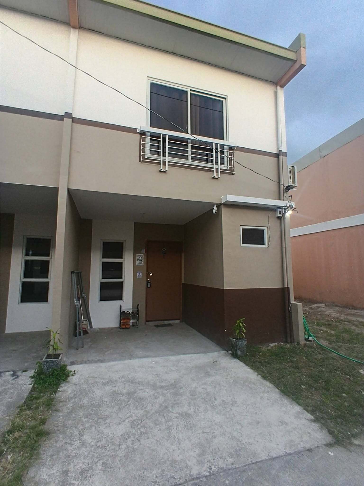 Un edificio de dos pisos con un balcón, una puerta y una ventana pequeña.