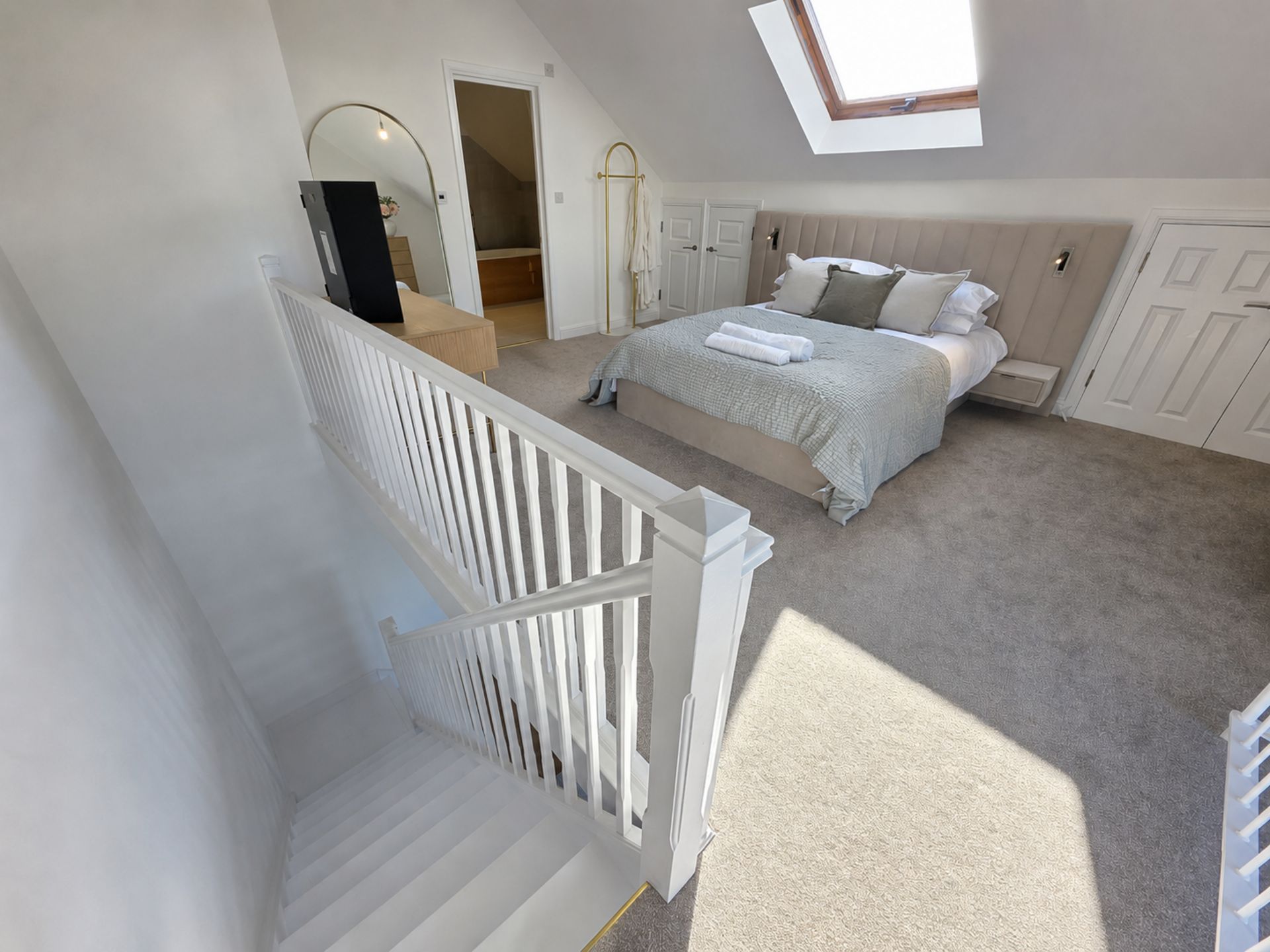 A bedroom with a bed, a window, a staircase, and a door.