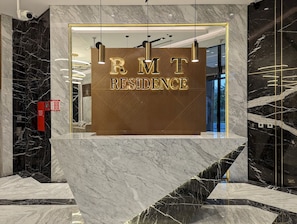 A reception desk with 'RMT RESIDENCE' signage, marble flooring, and modern lighting fixtures. - Stylish Studio Apartment at RMT  (Dubai)