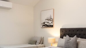 Un dormitorio con dos camas, ventilador de techo, ventana y aire acondicionado instalado en la pared.