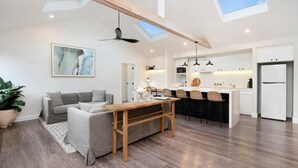 Un espacio habitable moderno con sofá, mesa de comedor, cocina y un tragaluz.