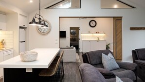 Una cocina moderna con encimera blanca, un reloj grande e iluminación colgante.