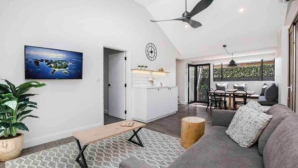 Un salon moderne avec un canapé, une table basse, un téléviseur et un ventilateur de plafond.